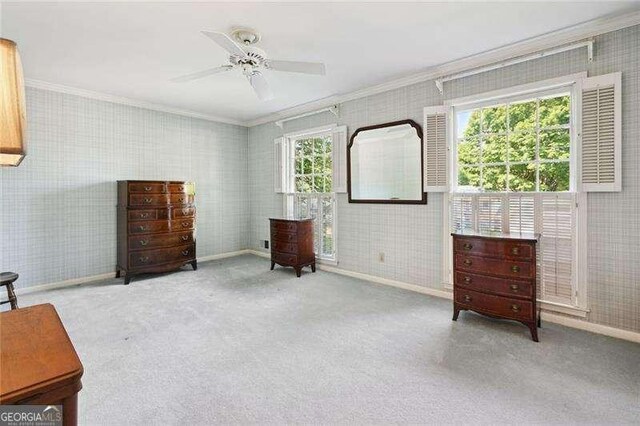 sitting room with carpet flooring, ornamental molding, wallpapered walls, and a ceiling fan