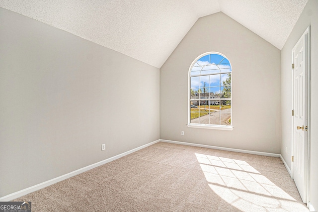 spare room with light carpet, vaulted ceiling, a textured ceiling, and baseboards