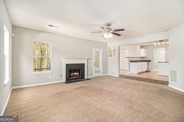 498 Pecan Wood Cir, Fairburn, GA 30213 - unfurnished living room featuring light carpet, a fireplace with flush hearth, a ceiling fan, and a textured ceiling