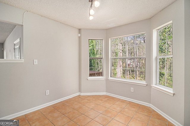 498 Pecan Wood Cir, Fairburn, GA 30213 - empty room featuring light tile patterned floors, a textured ceiling, track lighting, and healthy amount of natural light