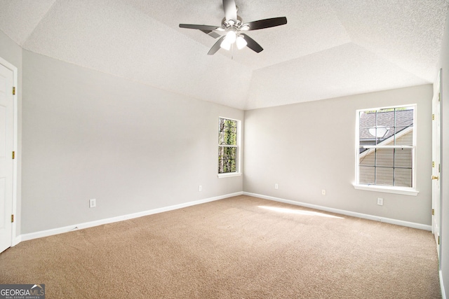 spare room with carpet, ceiling fan, baseboards, a textured ceiling, and lofted ceiling