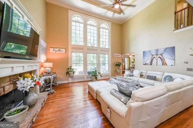 4408 Meadowwood Dr, Loganville, GA 30052 - living room with a ceiling fan, ornamental molding, a fireplace with raised hearth, and wood finished floors