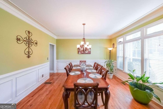 4408 Meadowwood Dr, Loganville, GA 30052 - dining area with light wood finished floors, crown molding, a chandelier, and visible vents