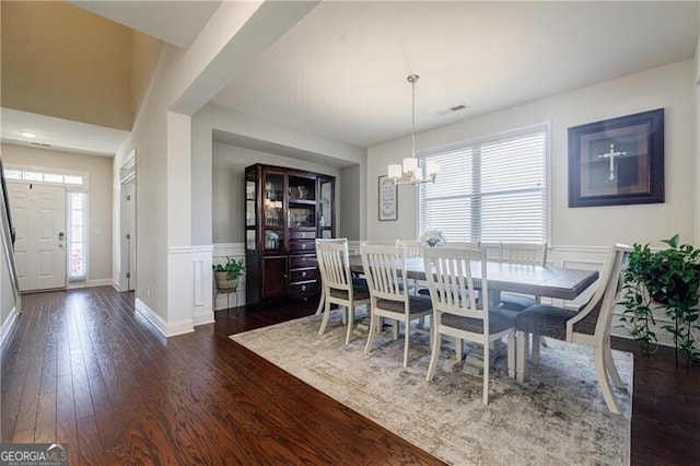4870 Odum View Ln, Cumming, GA 30040 - dining room featuring dark wood-style floors, a chandelier, wainscoting, and a decorative wall