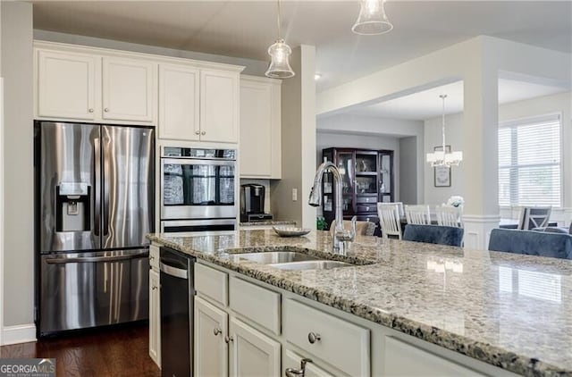 4870 Odum View Ln, Cumming, GA 30040 - kitchen with appliances with stainless steel finishes, light stone countertops, dark wood finished floors, decorative light fixtures, and white cabinets