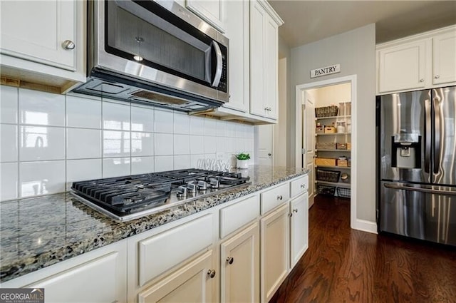 4870 Odum View Ln, Cumming, GA 30040 - kitchen with stainless steel appliances, dark wood finished floors, stone countertops, backsplash, and white cabinetry