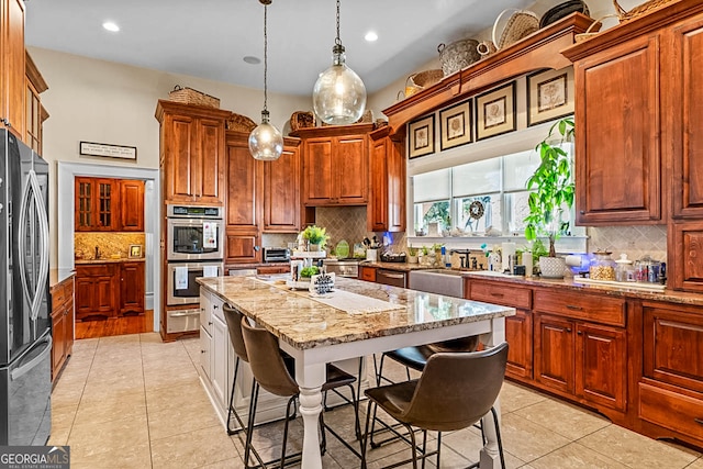 2173 Conyers St SE, Covington, GA 30014 - kitchen with appliances with stainless steel finishes, backsplash, a kitchen breakfast bar, light stone counters, and decorative light fixtures