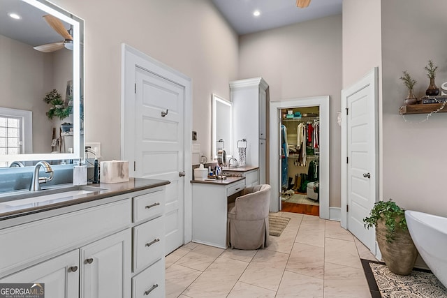 2173 Conyers St SE, Covington, GA 30014 - bathroom featuring ceiling fan, marble finish floors, vanity, a freestanding tub, and a towering ceiling