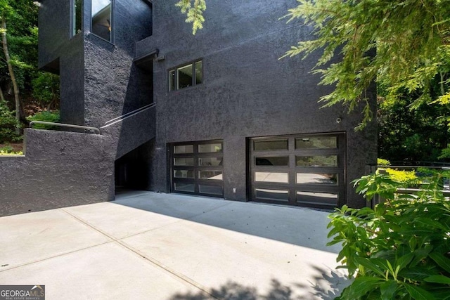 4 W Wesley Rdg NW, Atlanta, GA 30327 - back of house with a garage, stucco siding, driveway, and stone siding