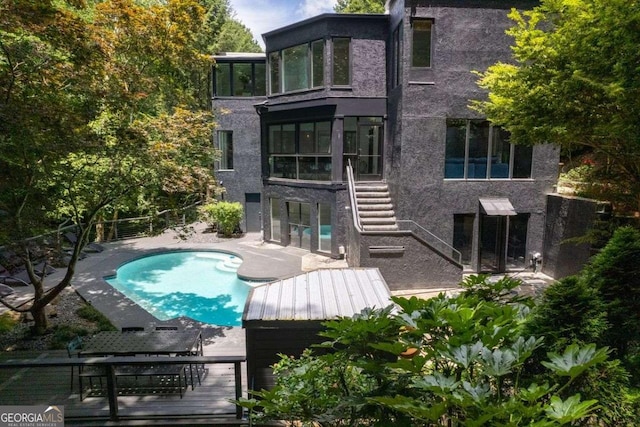 4 W Wesley Rdg NW, Atlanta, GA 30327 - back of property with stairway, a sunroom, a patio area, an outdoor pool, and stucco siding
