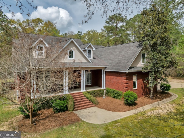 11 Creekwood Dr, Dublin, GA 31021 - cape cod home featuring stucco siding, a shingled roof, a porch, and brick siding