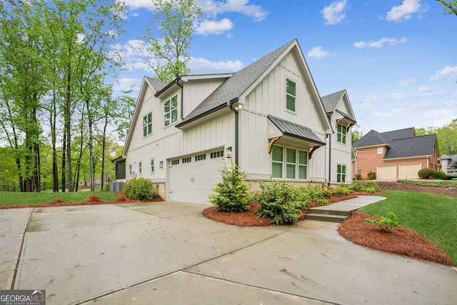 view of property exterior with cooling unit, board and batten siding, an attached garage, driveway, and roof with shingles