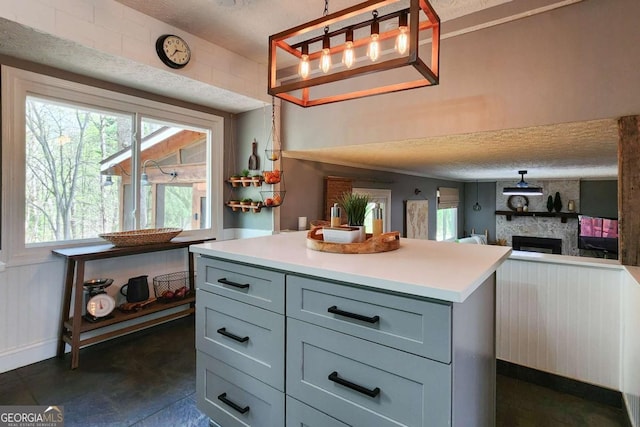 4295 S Berkeley Lake Rd NW, Berkeley Lake, GA 30096 - kitchen with a fireplace, gray cabinetry, light countertops, a textured ceiling, and hanging light fixtures