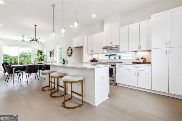 2029 Memorial Dr Unit 32, Atlanta, GA 30317 - kitchen featuring stainless steel electric range oven, under cabinet range hood, tasteful backsplash, light wood-style floors, and pendant lighting
