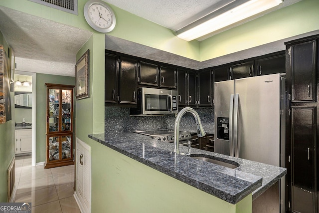 105 Governors Dr, Forest Park, GA 30297 - kitchen featuring a textured ceiling, a sink, dark cabinetry, and stainless steel appliances