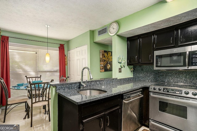 105 Governors Dr, Forest Park, GA 30297 - kitchen featuring dark stone countertops, a sink, appliances with stainless steel finishes, a peninsula, and dark cabinets