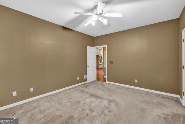 carpeted spare room featuring baseboards and ceiling fan