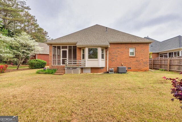 back of property with a sunroom, central AC, brick siding, and a yard