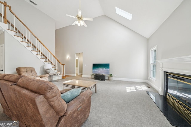 740 Trillium Ln, Lilburn, GA 30047 - carpeted living area with stairs, high vaulted ceiling, a ceiling fan, a skylight, and a glass covered fireplace