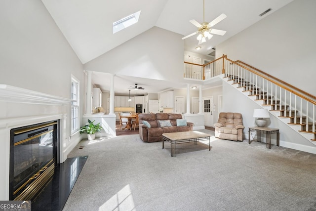 740 Trillium Ln, Lilburn, GA 30047 - carpeted living area featuring ceiling fan, high vaulted ceiling, stairway, a glass covered fireplace, and a skylight