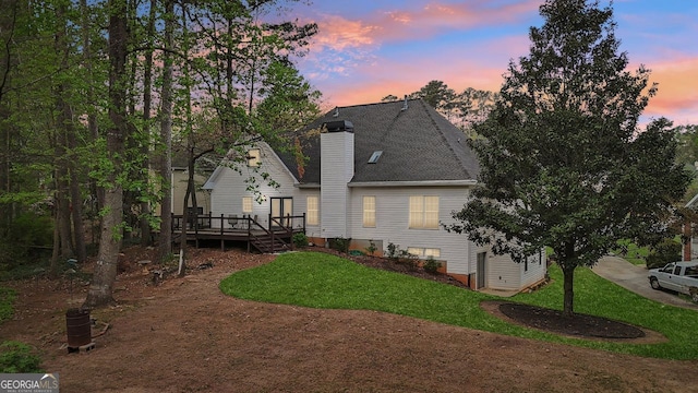 740 Trillium Ln, Lilburn, GA 30047 - back of property at dusk featuring a deck, a lawn, a chimney, and roof with shingles