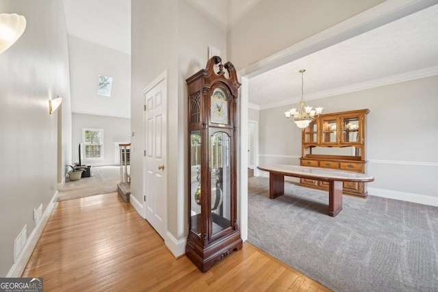 740 Trillium Ln, Lilburn, GA 30047 - hall with light wood finished floors, baseboards, a chandelier, a high ceiling, and light carpet