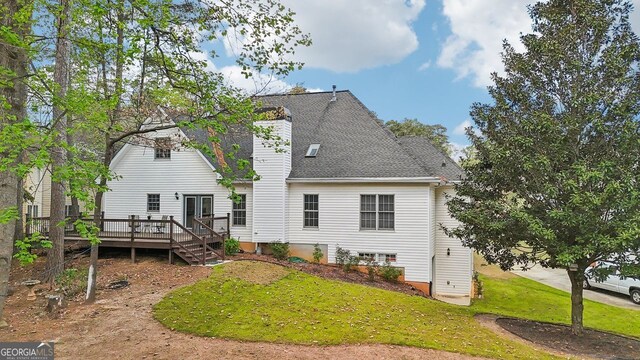 740 Trillium Ln, Lilburn, GA 30047 - back of property featuring a deck, a lawn, a chimney, and a shingled roof