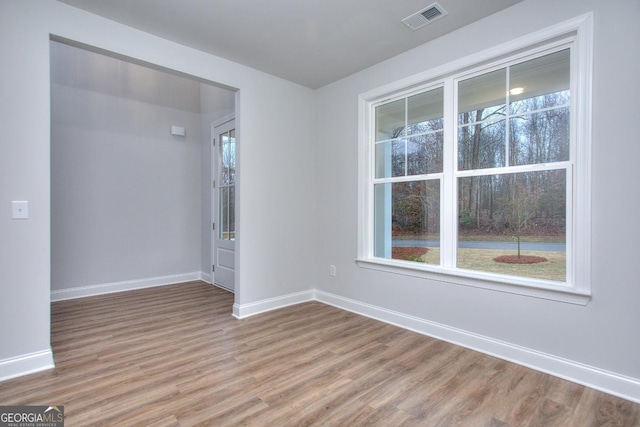 unfurnished room featuring light wood-style floors, baseboards, a healthy amount of sunlight, and visible vents