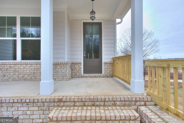 view of exterior entry with stone siding and a porch