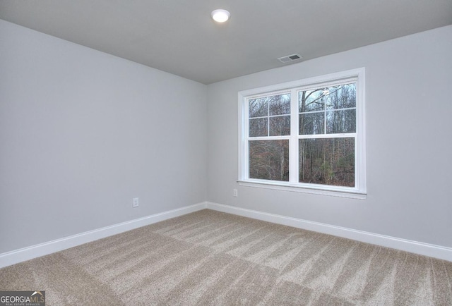spare room featuring baseboards, visible vents, and light colored carpet