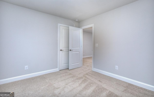 spare room with light colored carpet and baseboards
