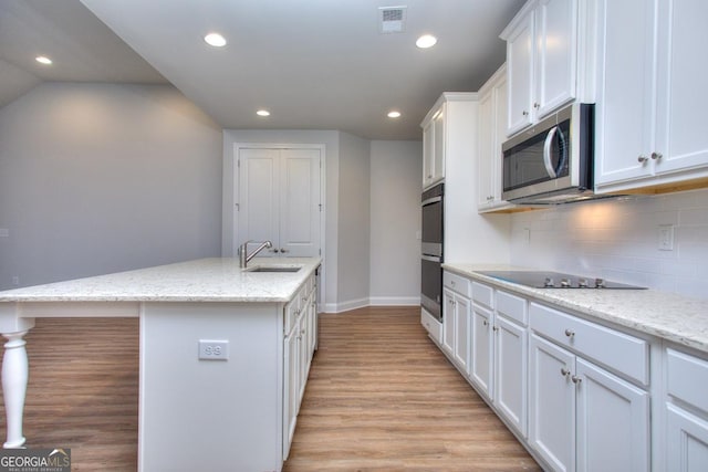 kitchen with white cabinetry, light wood-type flooring, a sink, visible vents, and appliances with stainless steel finishes