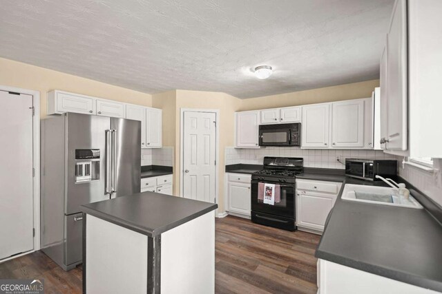 kitchen featuring white cabinets, a sink, dark countertops, and black appliances
