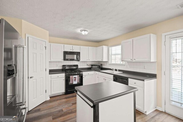 kitchen featuring dark wood-style floors, dark countertops, black appliances, and white cabinetry