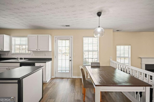 kitchen with white cabinetry, dark wood-style flooring, a sink, dark countertops, and visible vents