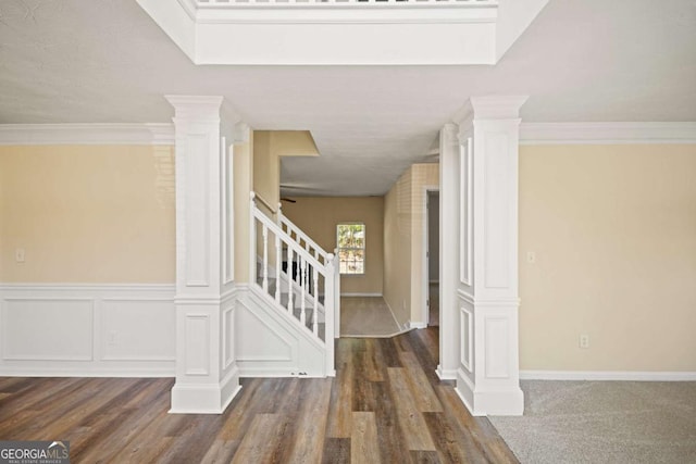 stairway with decorative columns, ornamental molding, and wood finished floors