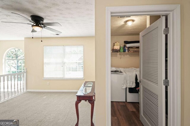 hall with washer and clothes dryer, dark carpet, baseboards, and a textured ceiling