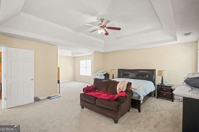 carpeted bedroom with baseboards, visible vents, a ceiling fan, and a raised ceiling
