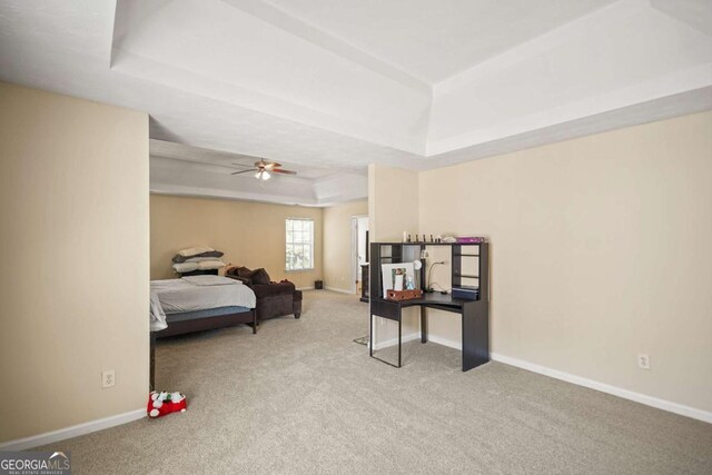 carpeted bedroom with baseboards and a raised ceiling