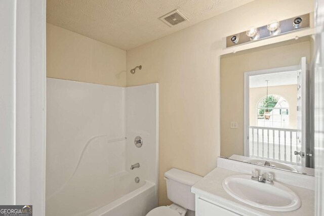 bathroom with a textured ceiling, visible vents, toilet, vanity, and shower / washtub combination