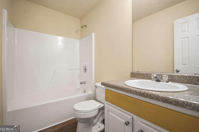 bathroom featuring washtub / shower combination, wood finished floors, toilet, and vanity