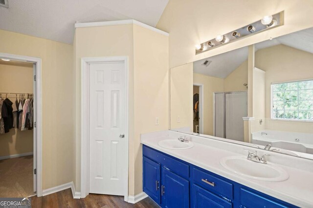 bathroom with a tub with jets, vaulted ceiling, and a sink