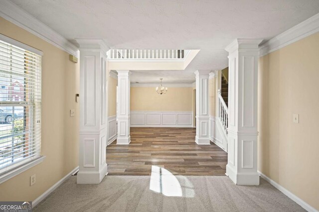 interior space featuring ornate columns, a notable chandelier, carpet, and crown molding
