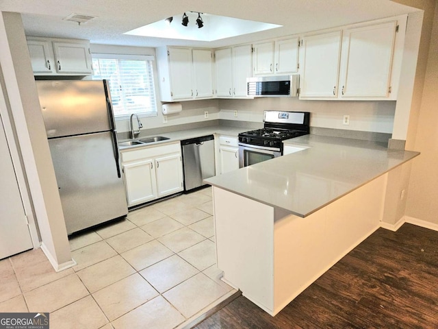 35 Rumson Ct SE, Smyrna, GA 30080 - kitchen with white cabinetry, stainless steel appliances, a raised ceiling, a sink, and a peninsula