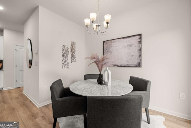 dining space with light wood-style flooring, baseboards, and a chandelier