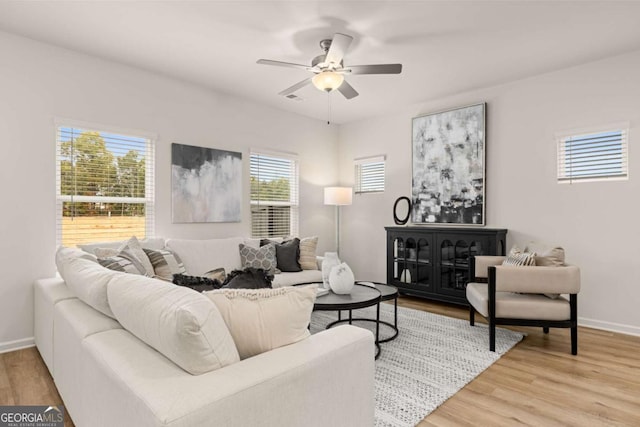 living area featuring visible vents, baseboards, light wood finished floors, and ceiling fan
