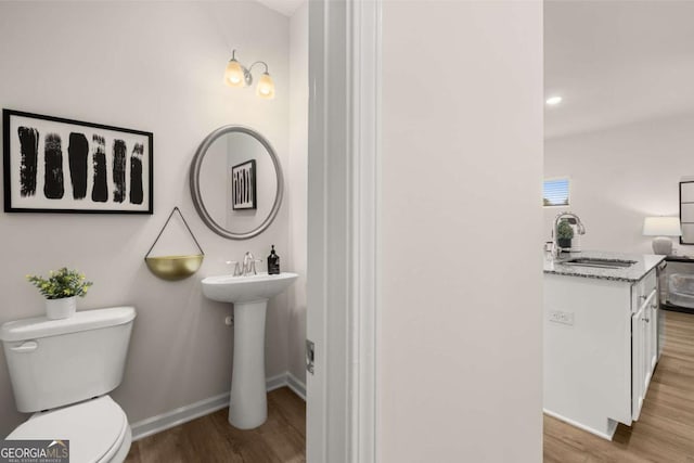 bathroom featuring baseboards, a sink, toilet, and wood finished floors