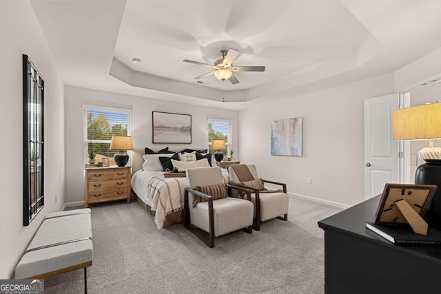 bedroom with visible vents, baseboards, ceiling fan, a raised ceiling, and light colored carpet