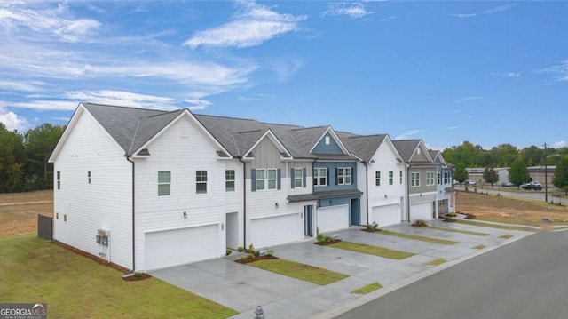 townhome / multi-family property featuring board and batten siding, a residential view, driveway, a front yard, and a garage