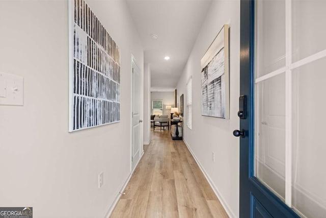hallway featuring baseboards, recessed lighting, and light wood finished floors